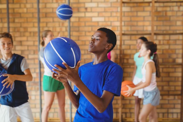 Teenagers practicing basketball in a gym, focusing on improving their skills. Ideal for use in educational materials, sports training guides, youth fitness programs, and promotional content for school sports activities.
