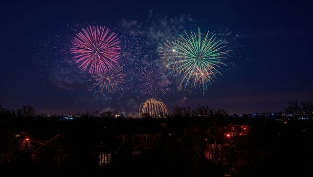 Vibrant fireworks illuminate night sky over suburban homes