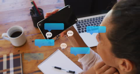 Chat Bubbles Emerging From Smartphone at Workspace