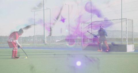 Field hockey penalty shot, red player preparing while goalkeeper guarding amid purple haze