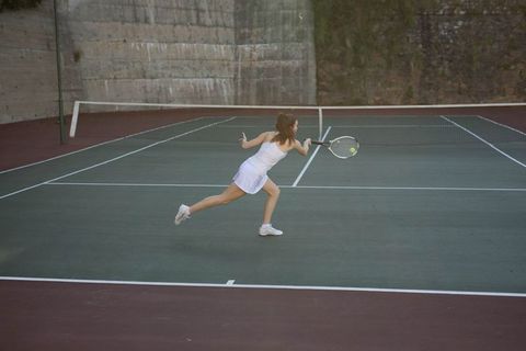 Female Tennis Player Powerfully Hitting Ball on Outdoor Court