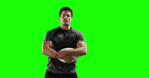 Confident Rugby Player Holding Ball on Green Screen Background