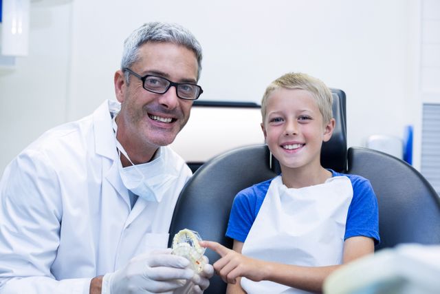 Dentist and young patient smiling in dental clinic. Ideal for use in healthcare, dental care promotions, pediatric dentistry advertisements, and educational materials on dental hygiene and dental checkups.