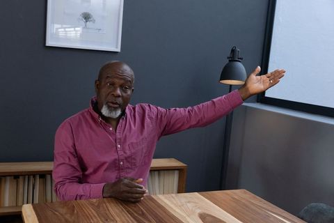 Senior Man Gesturing in Modern Office Space