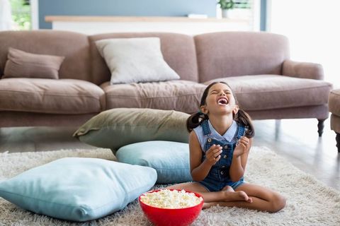 Cheerful Girl Enjoying Snack Time at Home with Popcorn