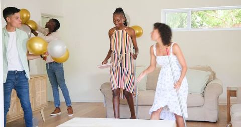 Friends preparing living room for celebration with balloons and cleaning