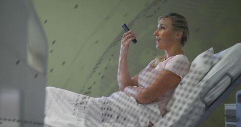 Woman undergoing mri scan holding smartphone while reclining in hospital bed