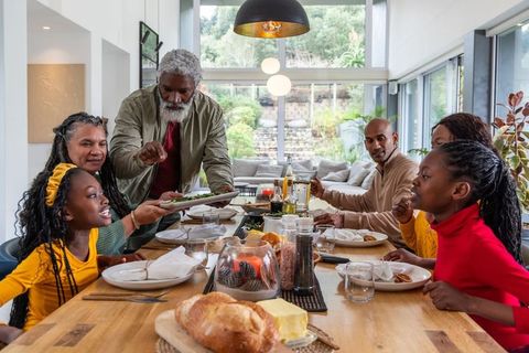 Multigenerational african american family gathering and sharing meal around modern dining table