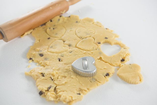 Close-up of rolling pin and cookie cutter on dough on white background
