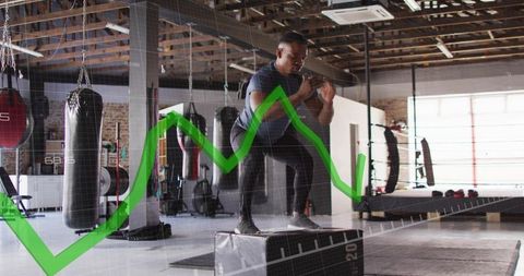 Male Athlete Performing Explosive Plyometric Box Jump in Gym with Green Performance Graph