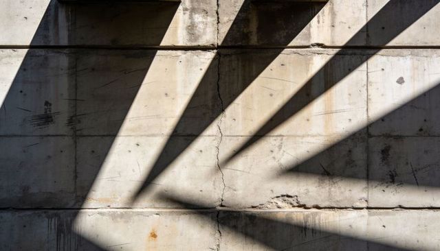Diagonal Beam Shadows on Weathered Concrete Wall with Prominent Central Vertical Crack