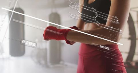 Woman boxer preparing with red hand wraps during high-intensity gym training