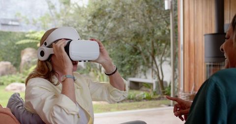 Senior Mother Experiencing Virtual Reality at Home with Daughter
