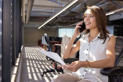 Smiling Professional Woman on Phone in Contemporary Office Setting