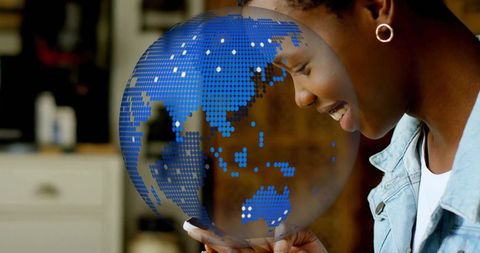 Woman interacting with digital globe on smartphone in kitchen setting