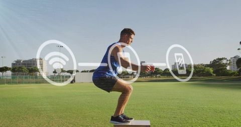 Male athlete performing box squat holding medicine ball with tech overlay on outdoor field