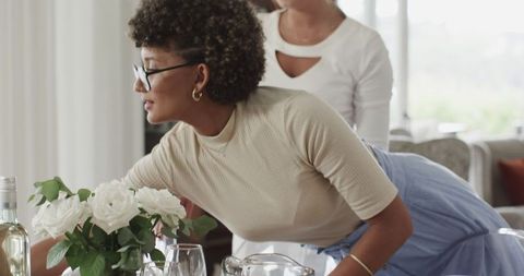 Woman arranging wedding table with flowers and glassware