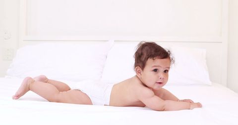 Adorable Baby Playing on Bed in White Diaper