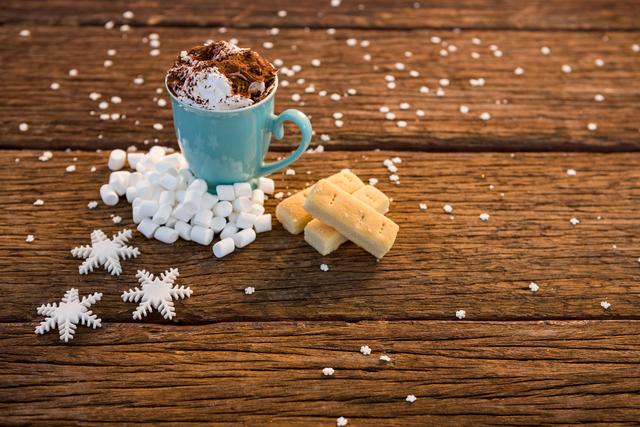 Cup of coffee with snowflake and marshmallow on wooden plank during christmas time
