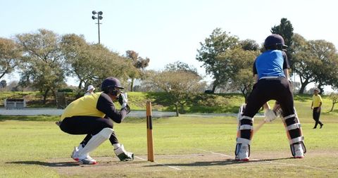 Batsman Crouching with Opponent Outdoor Cricket Match