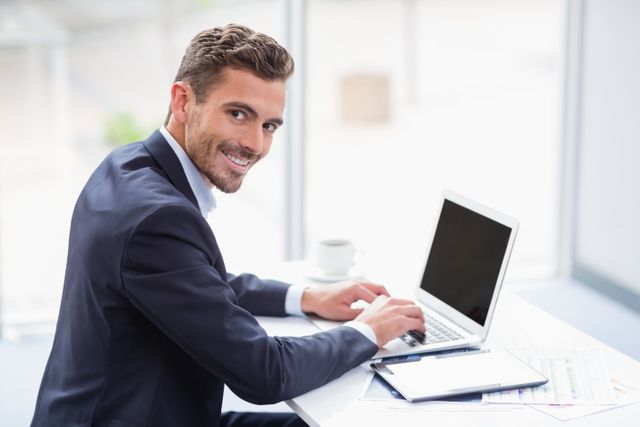 Portrait of a businessman using laptop at desk - Download Free Stock Photos Pikwizard.com