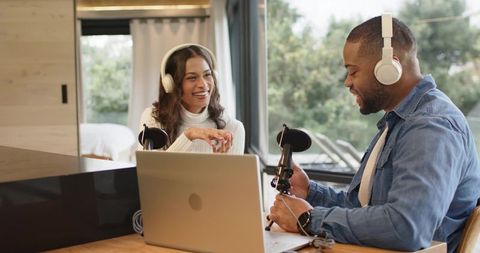 Diverse Podcasters Recording Together in Cozy Home Studio Using Laptop and Microphones