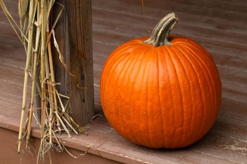 Autumn pumpkin on porch with straw decoration