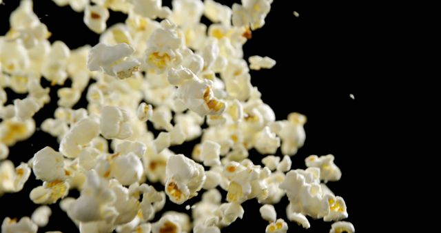 Popcorn kernels are captured mid-air against a black background, with copy space - Download Free Stock Photos Pikwizard.com