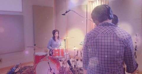 Musicians collaborating in soundproof studio with drums and microphone