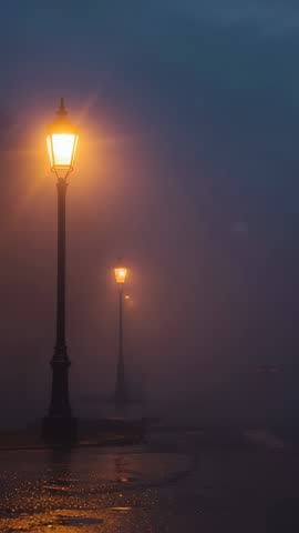 Vertical video glowing lampposts piercing dense fog over wet waterfront path, moody night