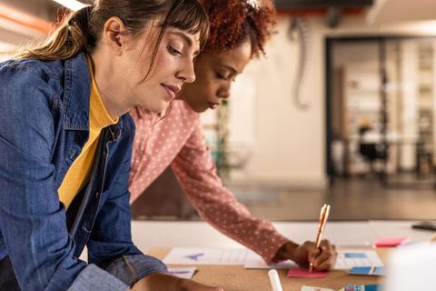 Diverse Female Coworkers Planning Project with Sticky Notes in Modern Office