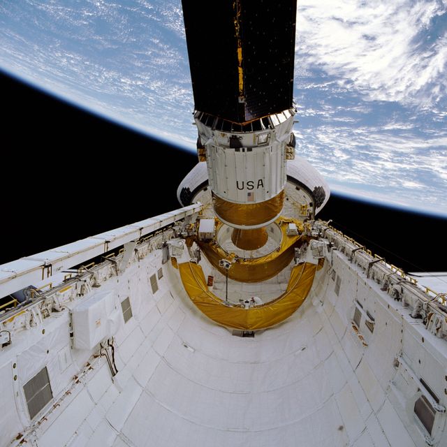 Tracking and Data Relay Satellite (TDRS-D) tilted in Shuttle Discovery's cargo bay. Ideal for education on space missions, NASA technology, and satellite deployment.