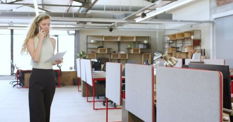 Woman on phone holding documents in modern office