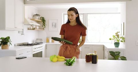 Woman Arranging Fresh Produce in Minimalist Kitchen Setting