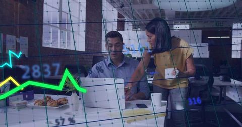Collaborative duo reviewing laptop analytics in modern open-plan office with coffee