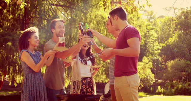 Group of friends having fun while barbecuing in a sunny park, enjoying food and drinks together. Ideal for concepts like social gatherings, enjoying summer, outdoor activities, friendship, and leisure time.