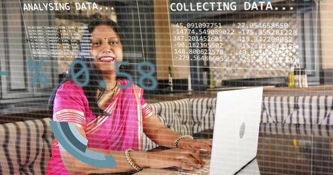 Indian analyst working on laptop with augmented data overlays in modern cafe