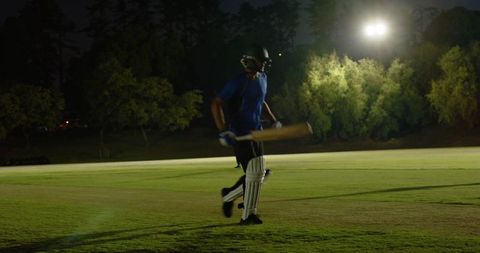 Teen cricketer walking to crease during floodlit training reacting to bowler run-up