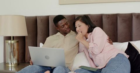 Couple Relaxing on Bed with Laptop and Smartphone