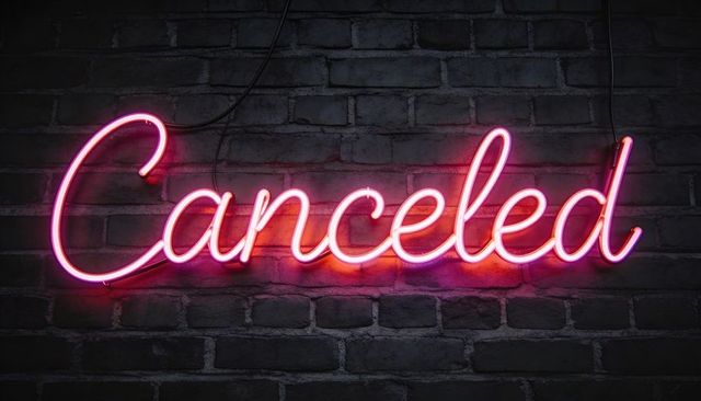 Glowing cursive neon canceled sign in pink magenta on exposed brick background