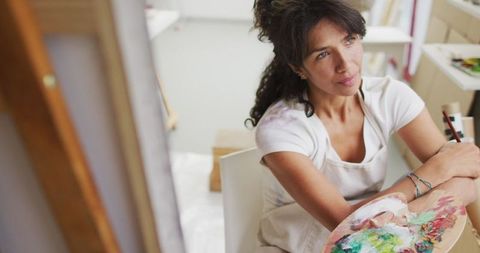 Female Artist Pondering with Paint Palette in Bright Studio - Download Free Stock Images Pikwizard.com