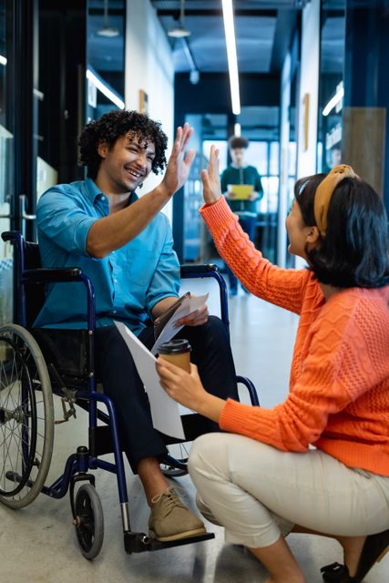 Happy disabled and diverse business people high fiving in office. Global business and working in office concept.