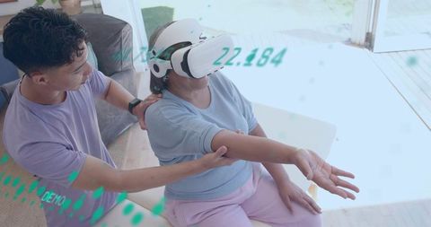 Senior receiving vr rehabilitation at home while caregiver guides arm support