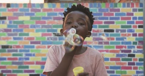 Child blowing bubbles in colorful outdoor environment