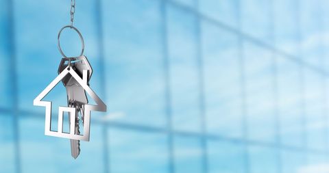 House-Shaped Keychain with Keys Against Glass Building