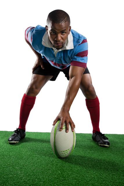 Male rugby player in uniform standing on green field, holding rugby ball, preparing to pass. Ideal for sports advertisements, fitness promotions, team spirit campaigns, and athletic training materials.