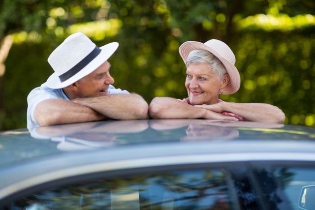 Senior couple looking at each other while leaning on car roof - Download Free Stock Photos Pikwizard.com