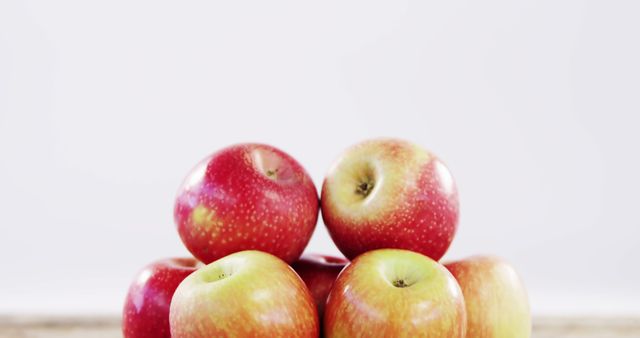 A pyramid of red and yellow apples is arranged against a soft, neutral background, with copy space. Fresh and ripe, these fruits suggest health and nutrition themes.