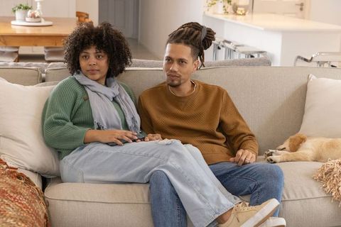 African american couple sitting closely on cozy beige sofa with sleeping golden retriever