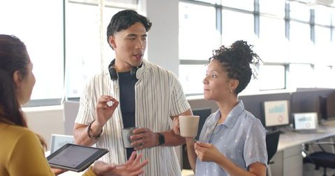 Diverse Professionals Having Coffee and Collaborating in Bright Open-Plan Office Space